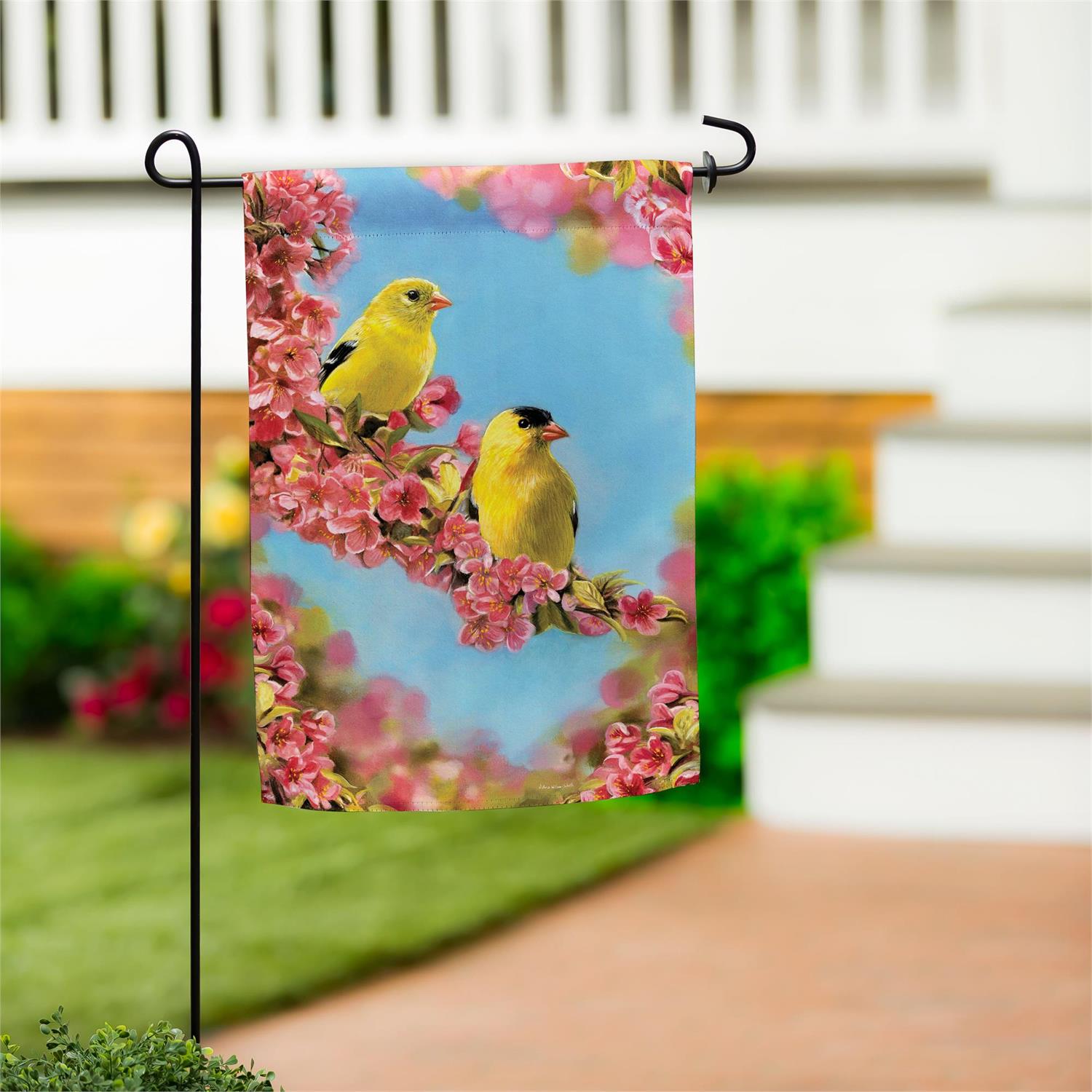 Goldfinches perched among sunlit flowers and greenery